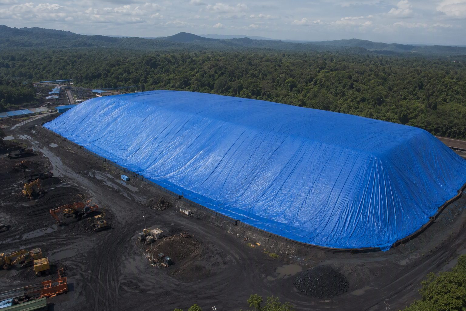 Terpal jumbo menutup tumpukan material di area stockpile tambang